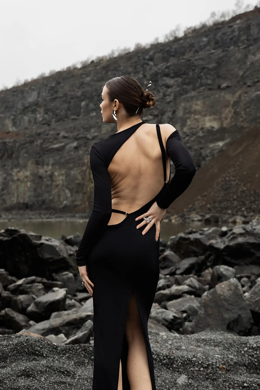 Photo éditorial, shooting magazine dans un paysage de roches noires, mannequin de dos.