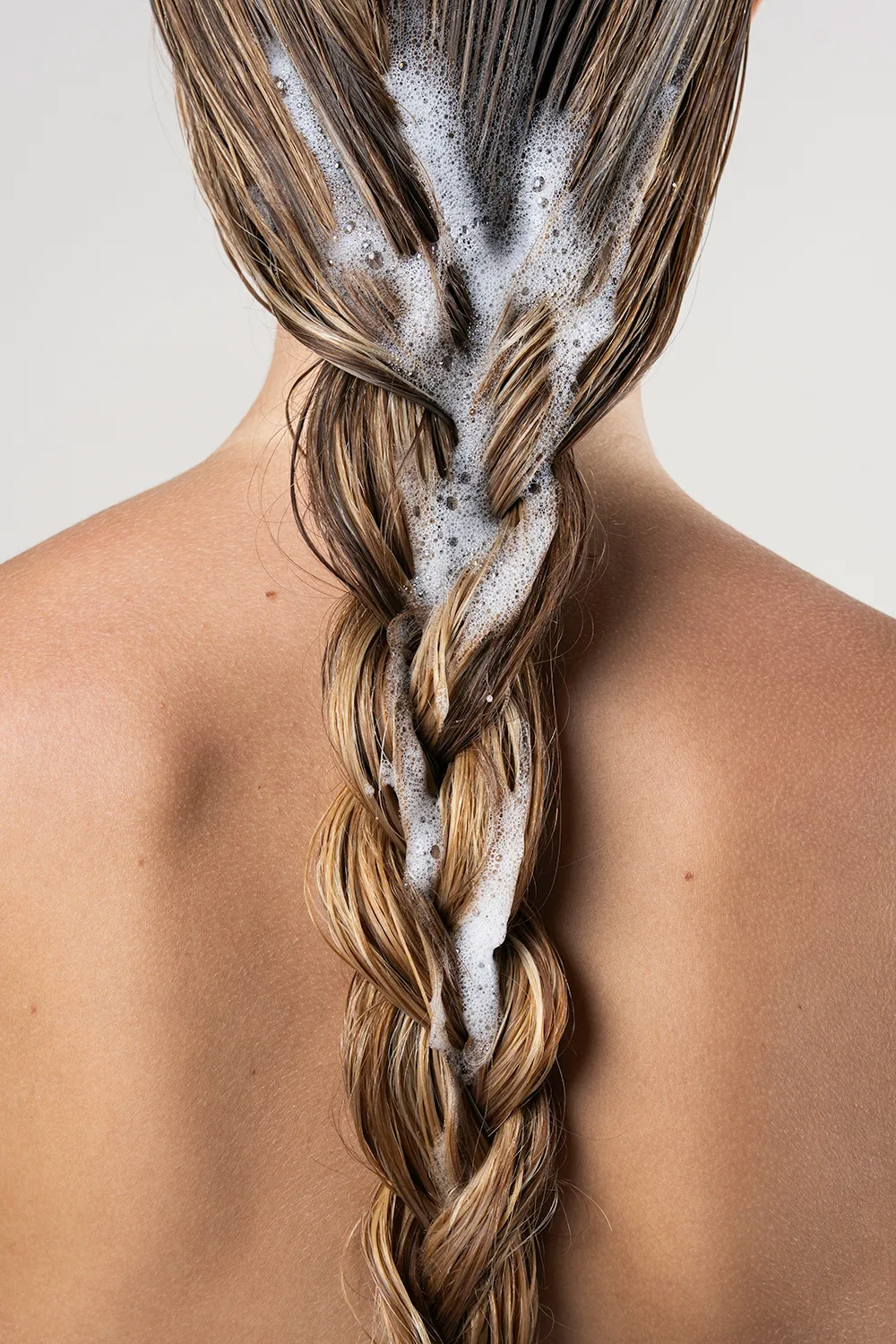 Shooting cosmétique, gros plan d'une chevelure tressée mouillé, focus sur la mousse.
