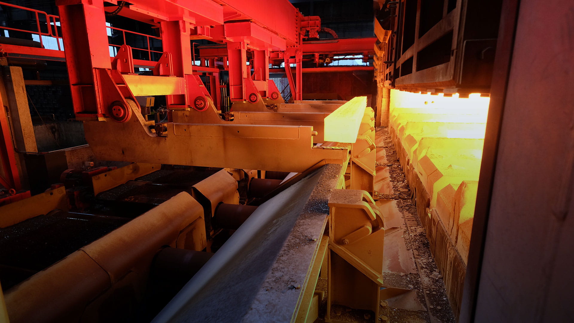 Industrial furnace with glowing hot metal slabs on a conveyor system inside a factory