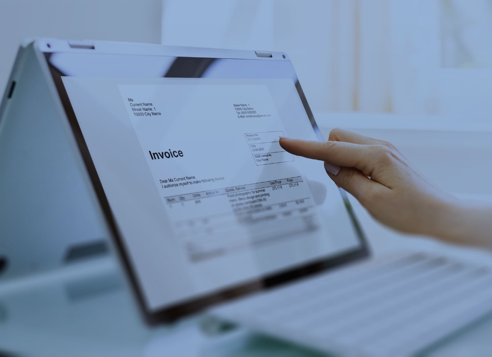 A person uses a touchscreen laptop to view an invoice document displayed on the screen.
