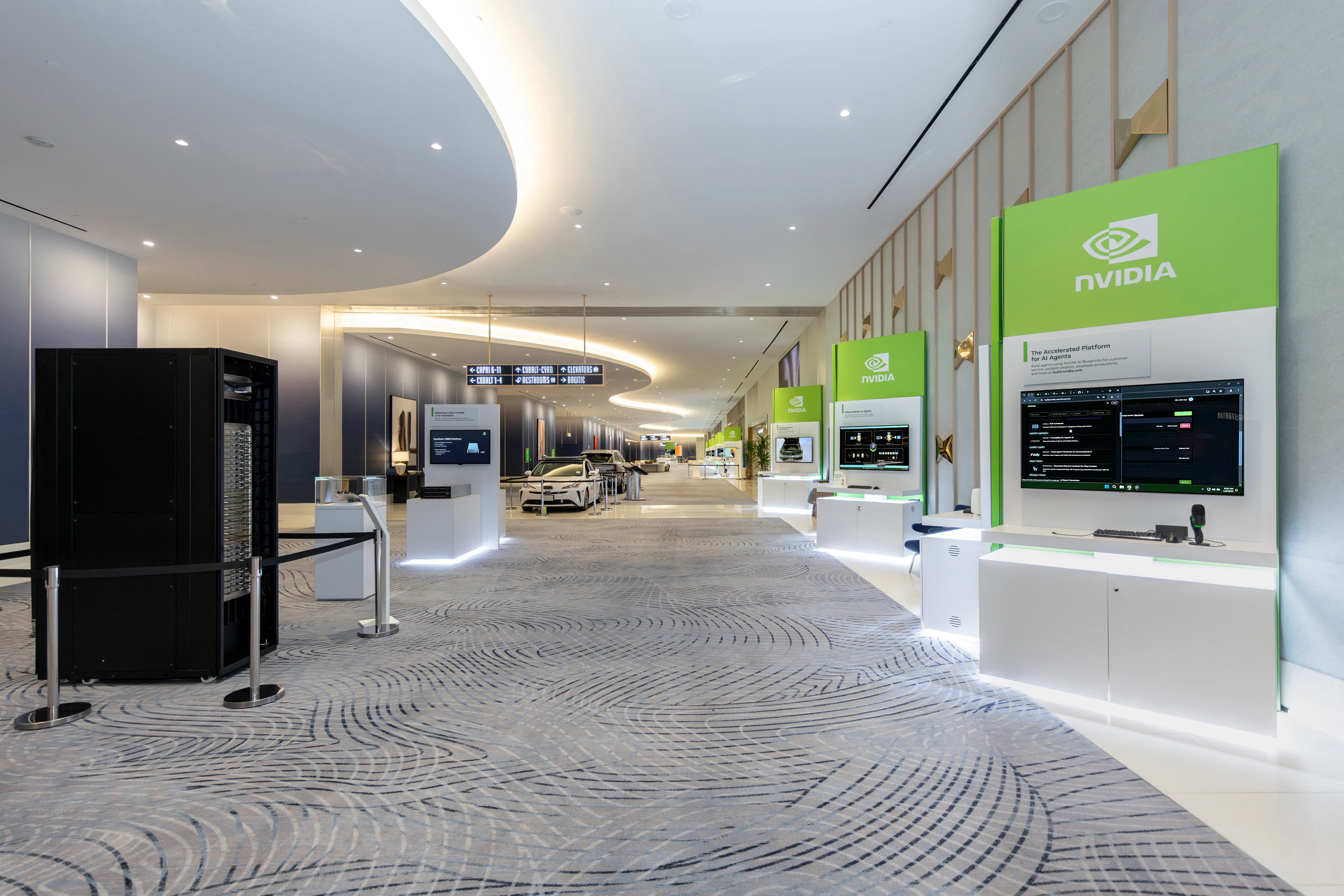 Spacious, modern hallway of a tech event, showcasing NVIDIA exhibits with green signage. Displays show tech content, while sleek decor creates a futuristic vibe.