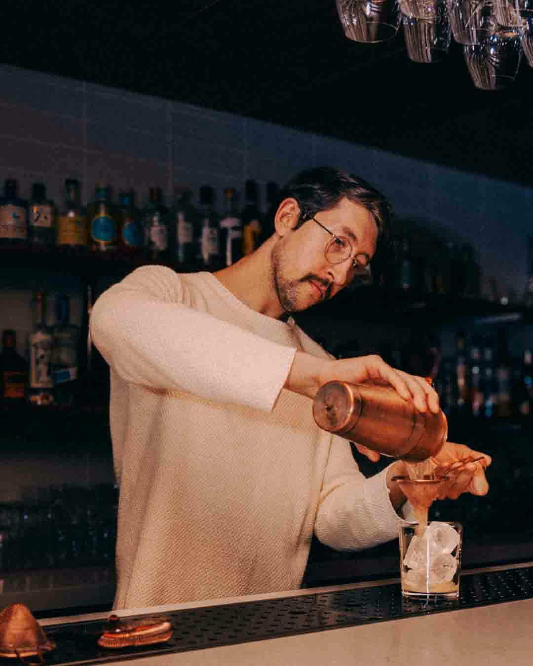 Bartender pouring cocktail behind the bar at Sara Restaurant in Toronto