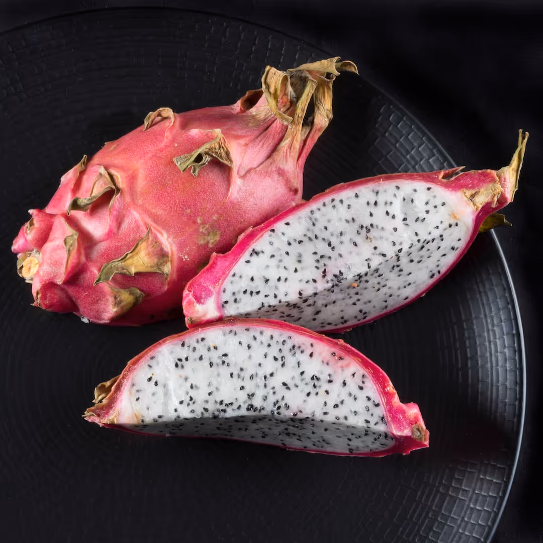 Dragon fruit growing on a cactus plant.