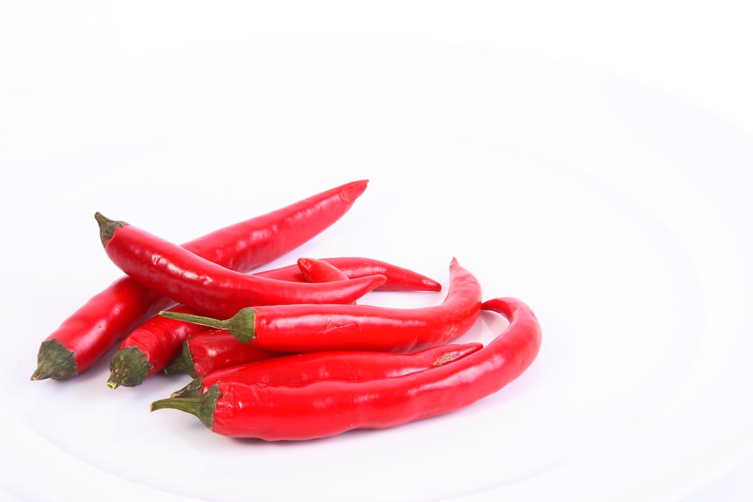 Red cayenne peppers growing on a plant.