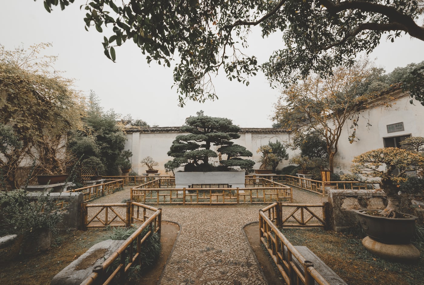 Chinese garden with traditional architecture, lush greenery, and water features.