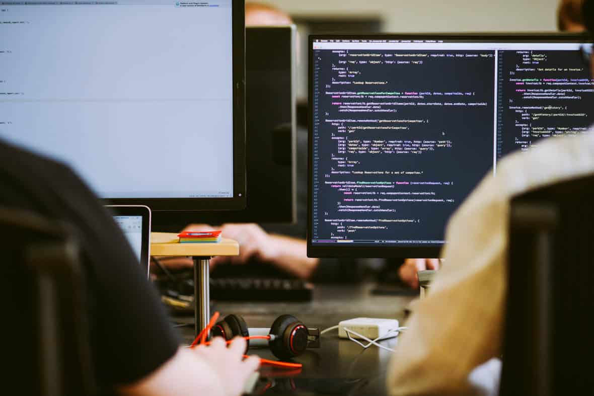 Two developers look at code on a monitor. Post title: C# Finally Has First-Class CLI Scripting in .NET 10