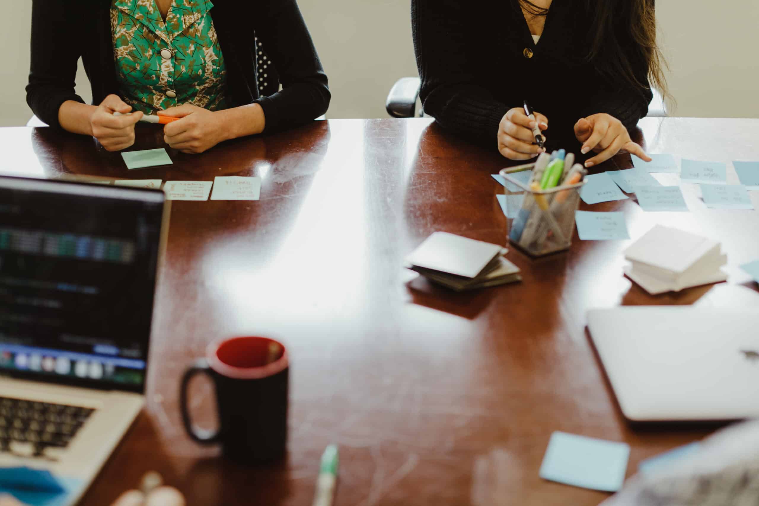 Anonymous people around a business table with sticky notes and laptops. Post title: How I Know When It’s Time to Add Lightweight QA on a Startup Project