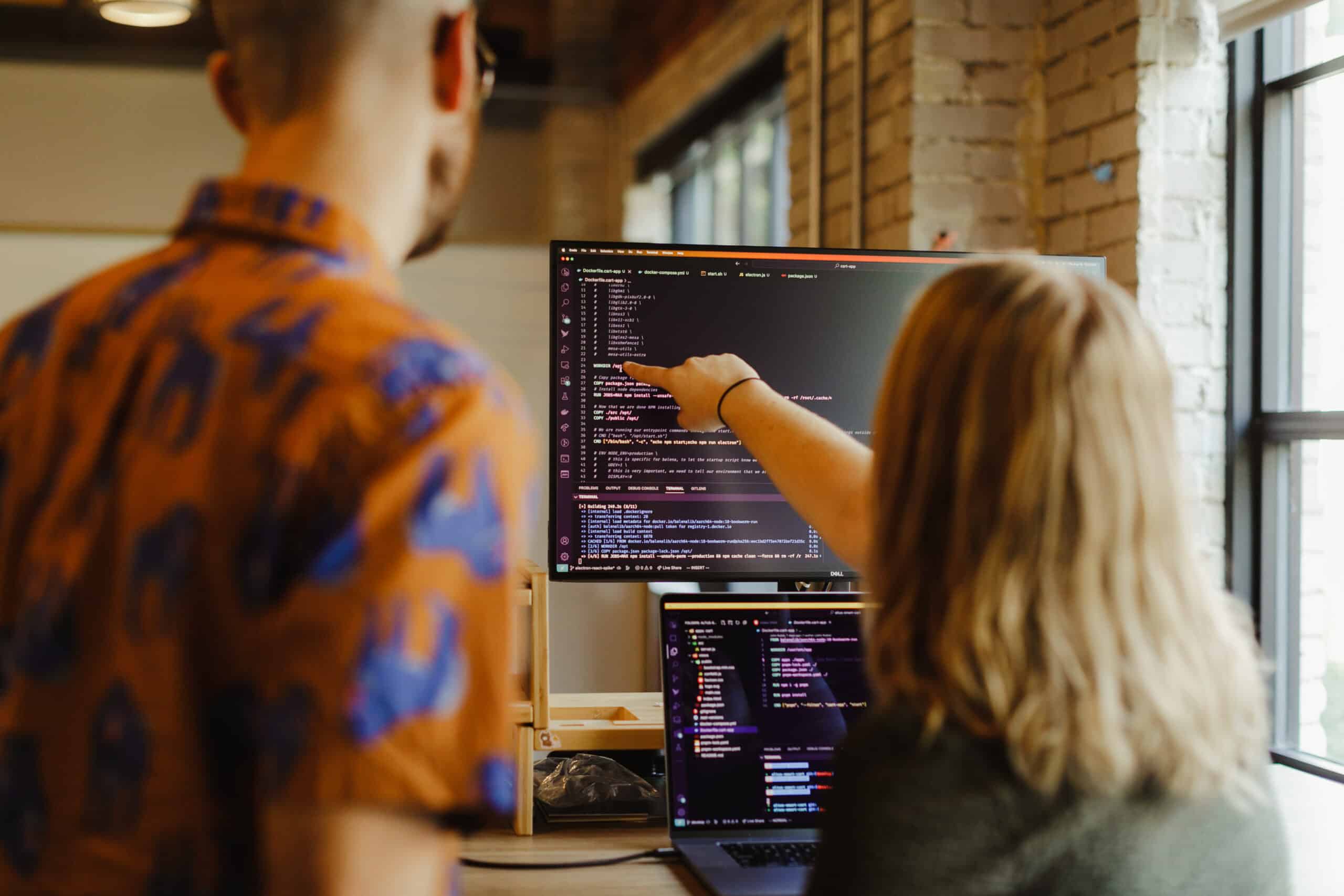 A developer gestures at a monitor while talking to her co-worker. Post title: How to Choose Among Class, Record, and Struct in C#