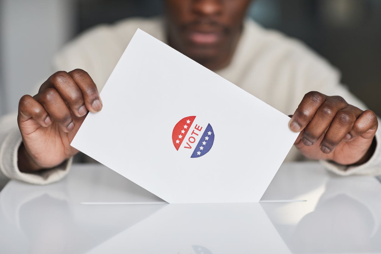 A person casting a ballot into a ballot box