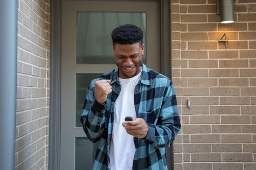 Man celebrates while looking at phone