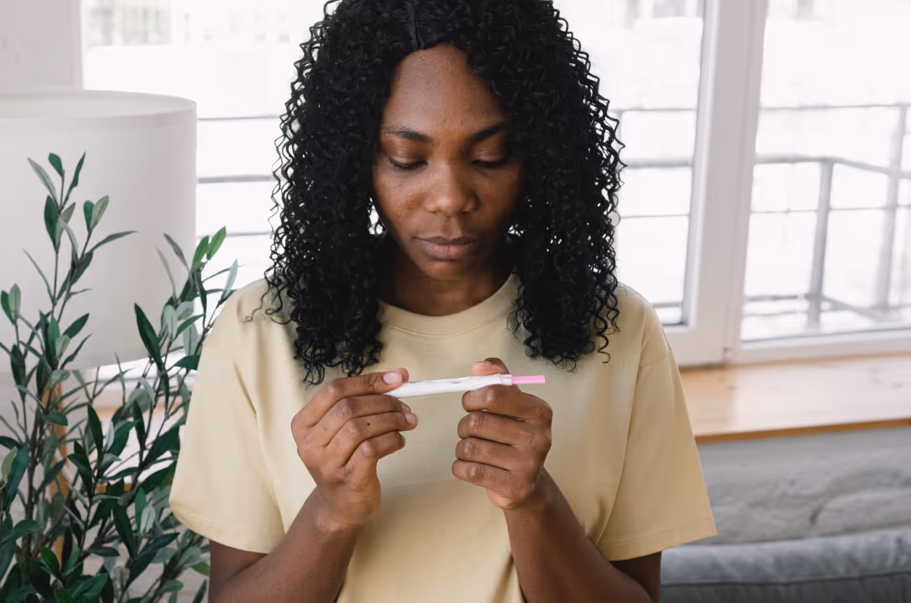 Woman with curly hair looking at a pregnancy test seriously