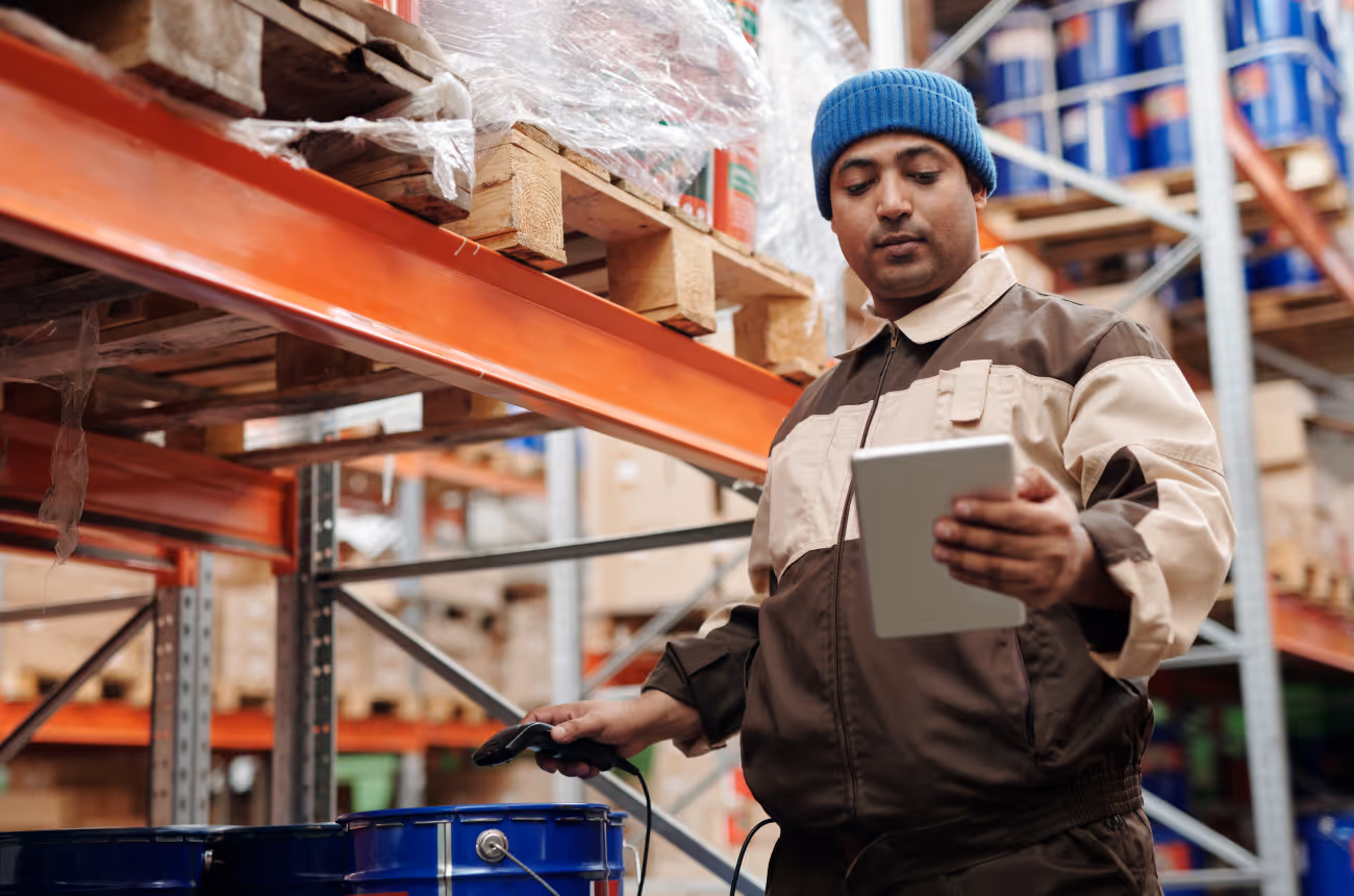 warehouse worker looking at device while scanning a bucket