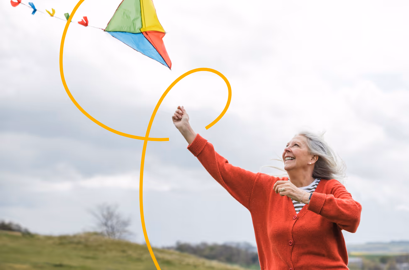 Older woman flying a kite on a cloudy day
