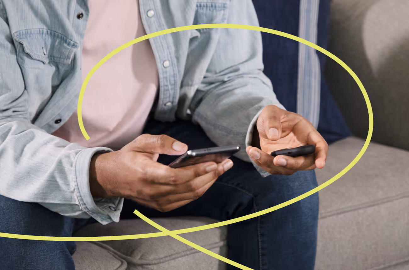 Man sitting on couch holding Pivot Breath Sensor viewing his carbon monoxide reading and looking at phone