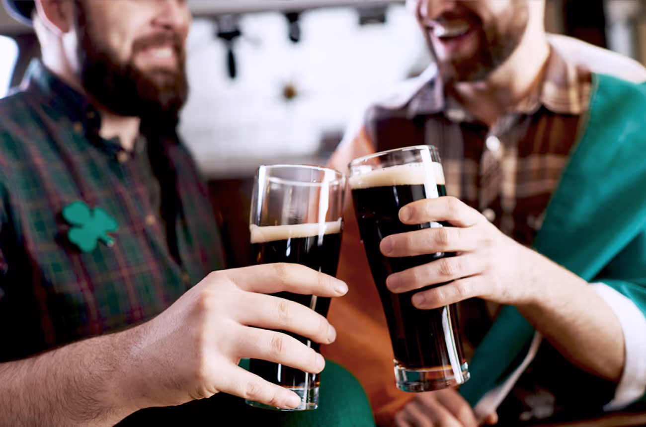 two men wearing flannel shirts cheers-ing beer together 