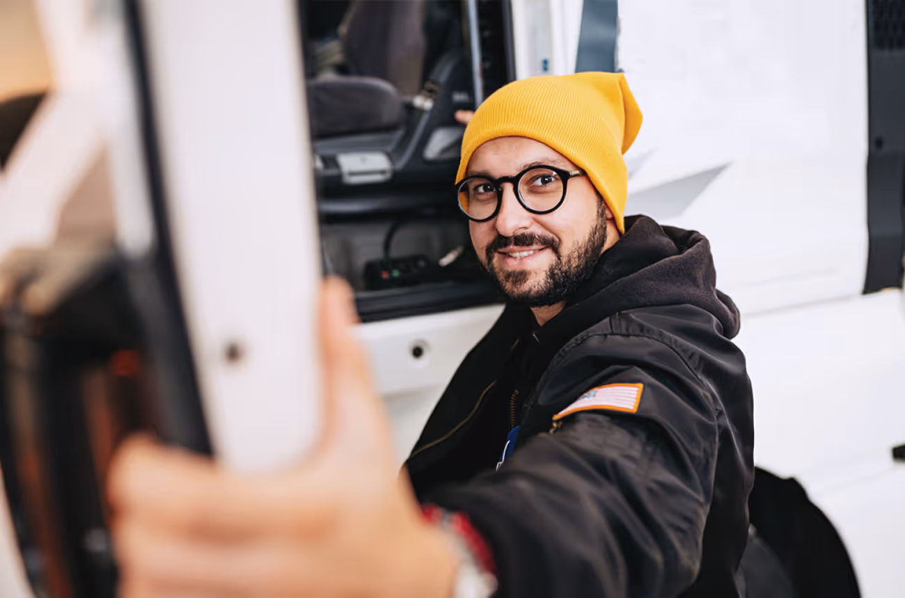 man in glasses wearing a yellow hat getting into a vehicle