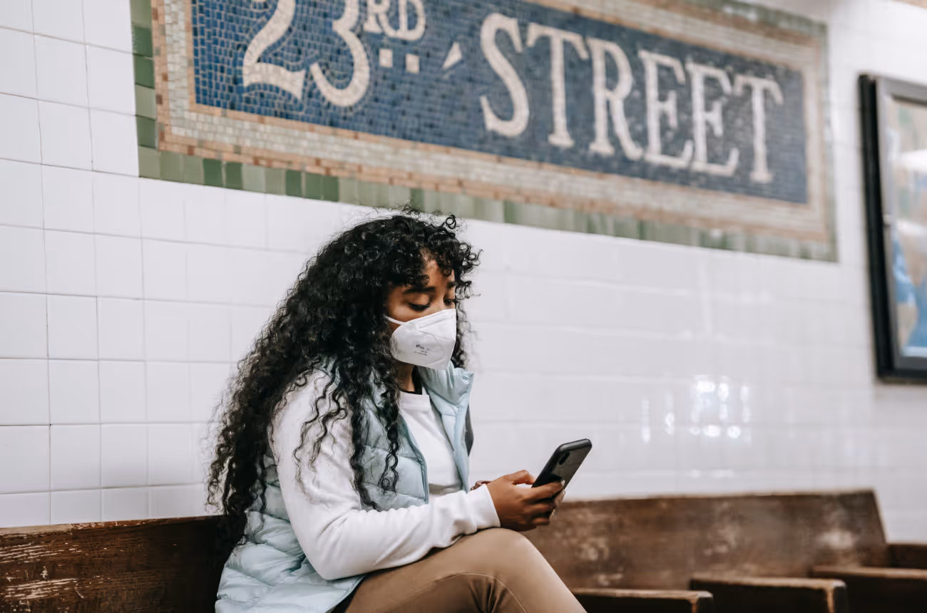 Woman wearing mask in subway station looking at phone