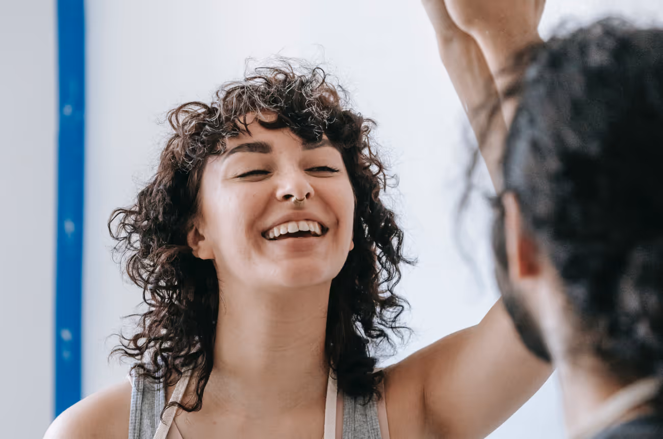 Woman with curly hair laughing at man with hair in bun