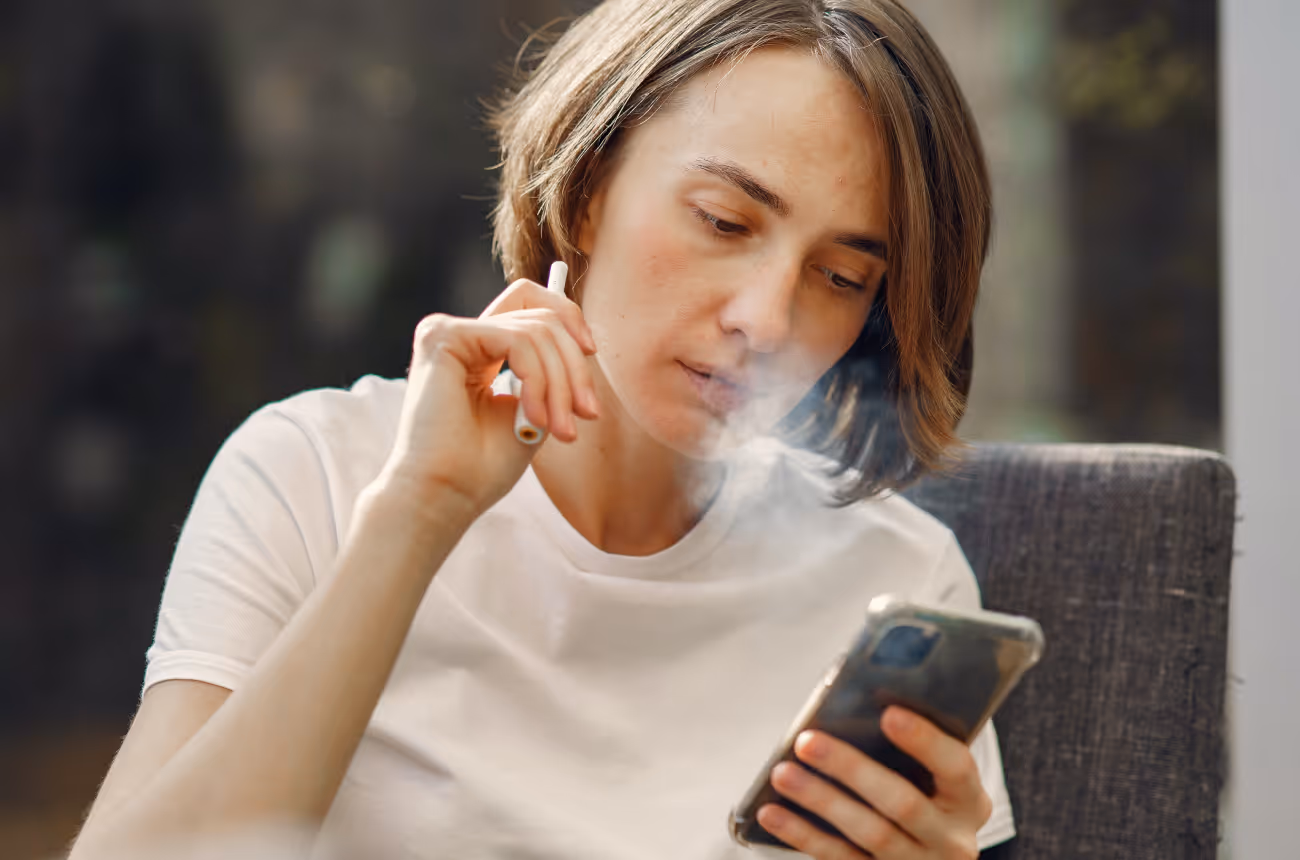 woman smoking a cigarette looking at a phone 