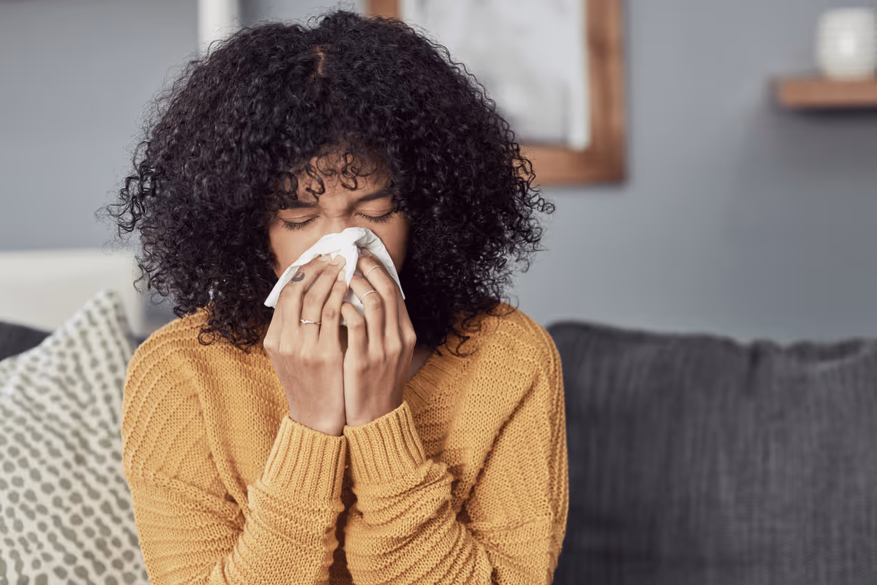 sick young woman blowing nose into a tissue
