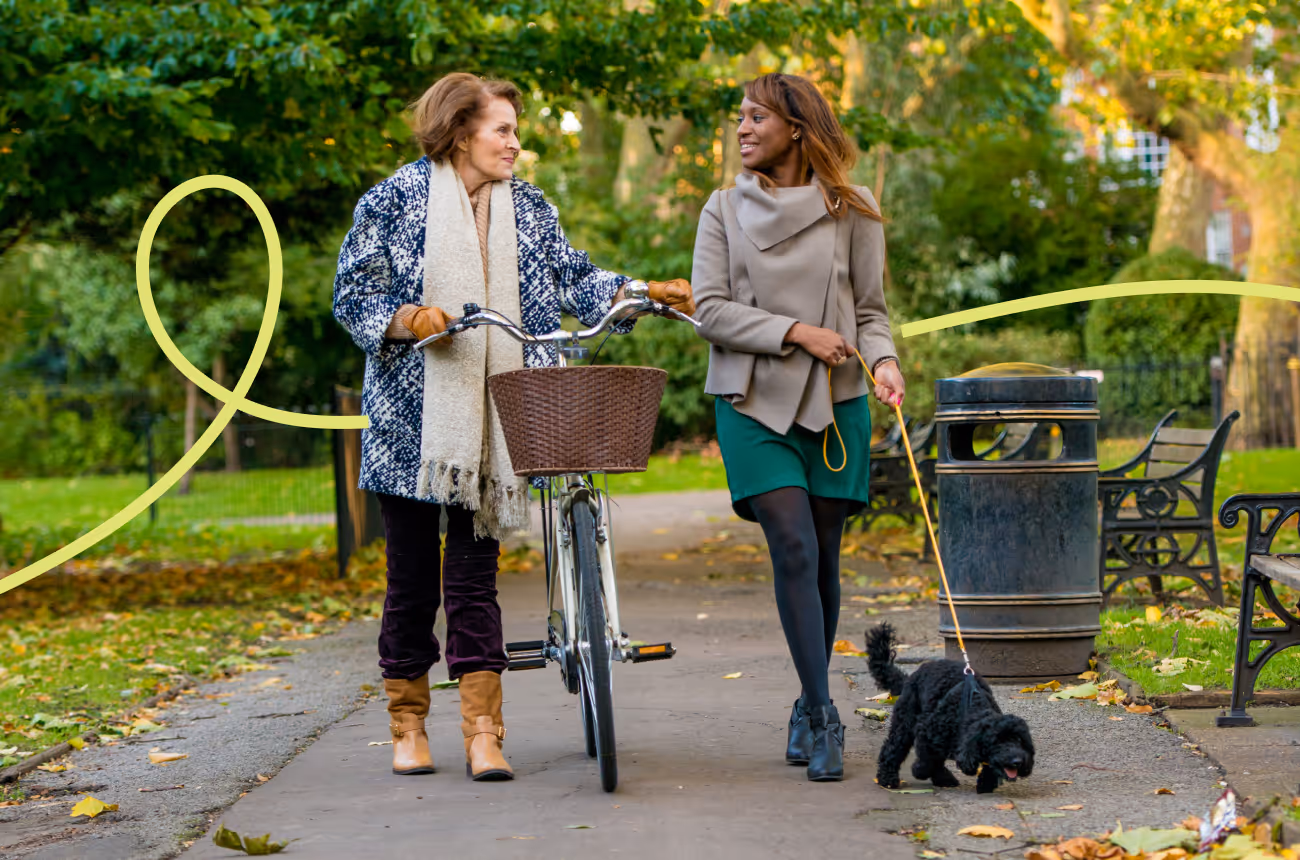 two women walking, one with a bike, the other with a dog