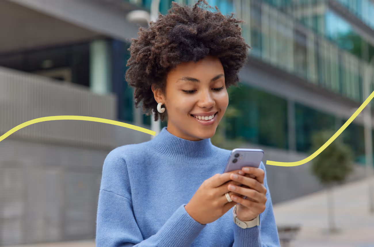 woman in blue sweater smiling at cell phone
