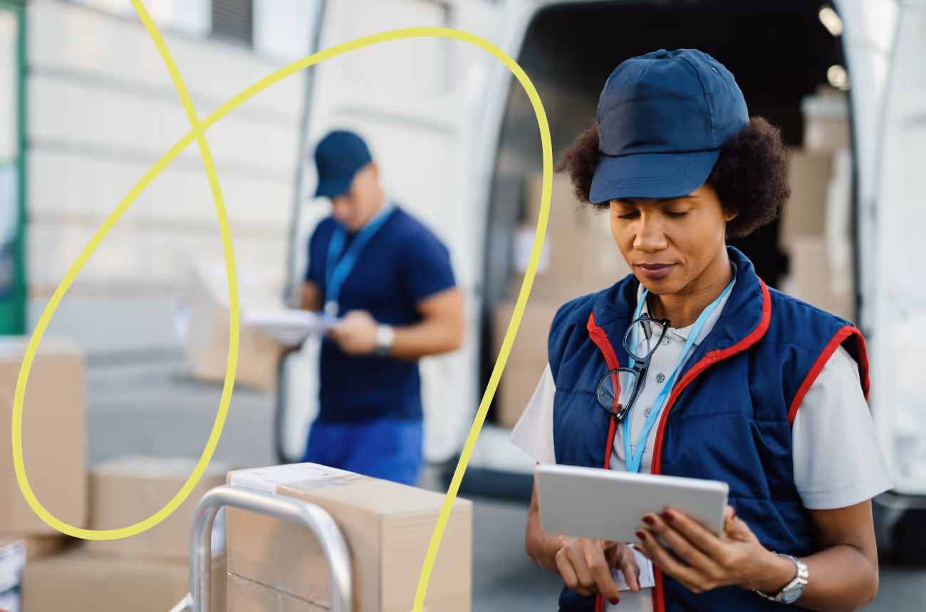 woman wearing a har looking at a clipboard while someone behind her unloads a van