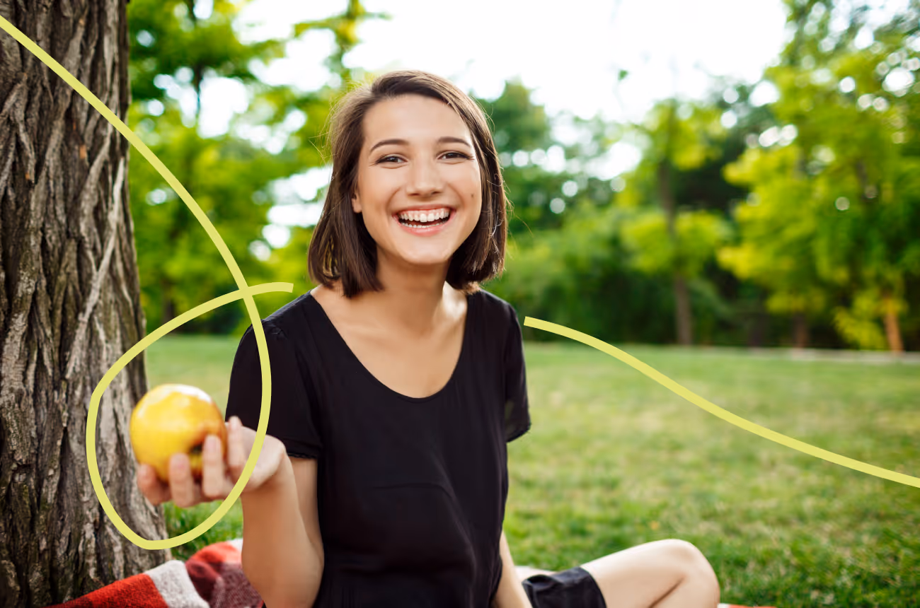 woman holding apple sitting in a park