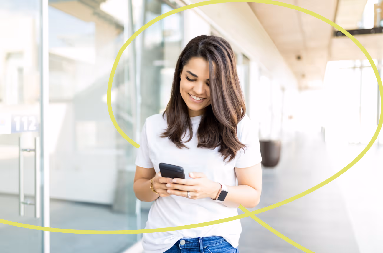woman smiling while looking at cell phone