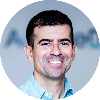 Smiling man with short dark hair wearing light blue collared shirt in circular profile photo frame.