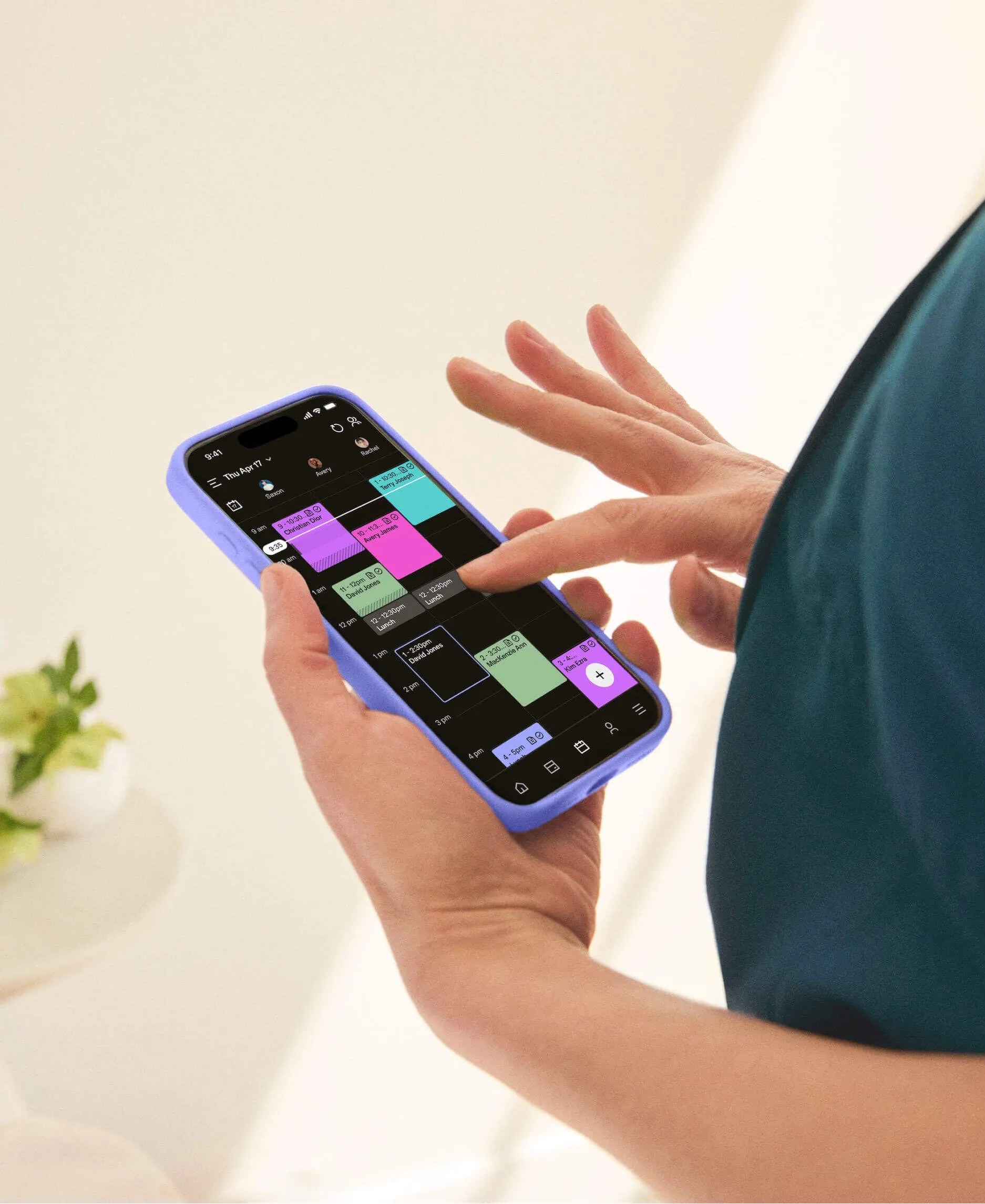 User interacting with a smartphone displaying GlossGenius’sa medical spa management software calendar interface.