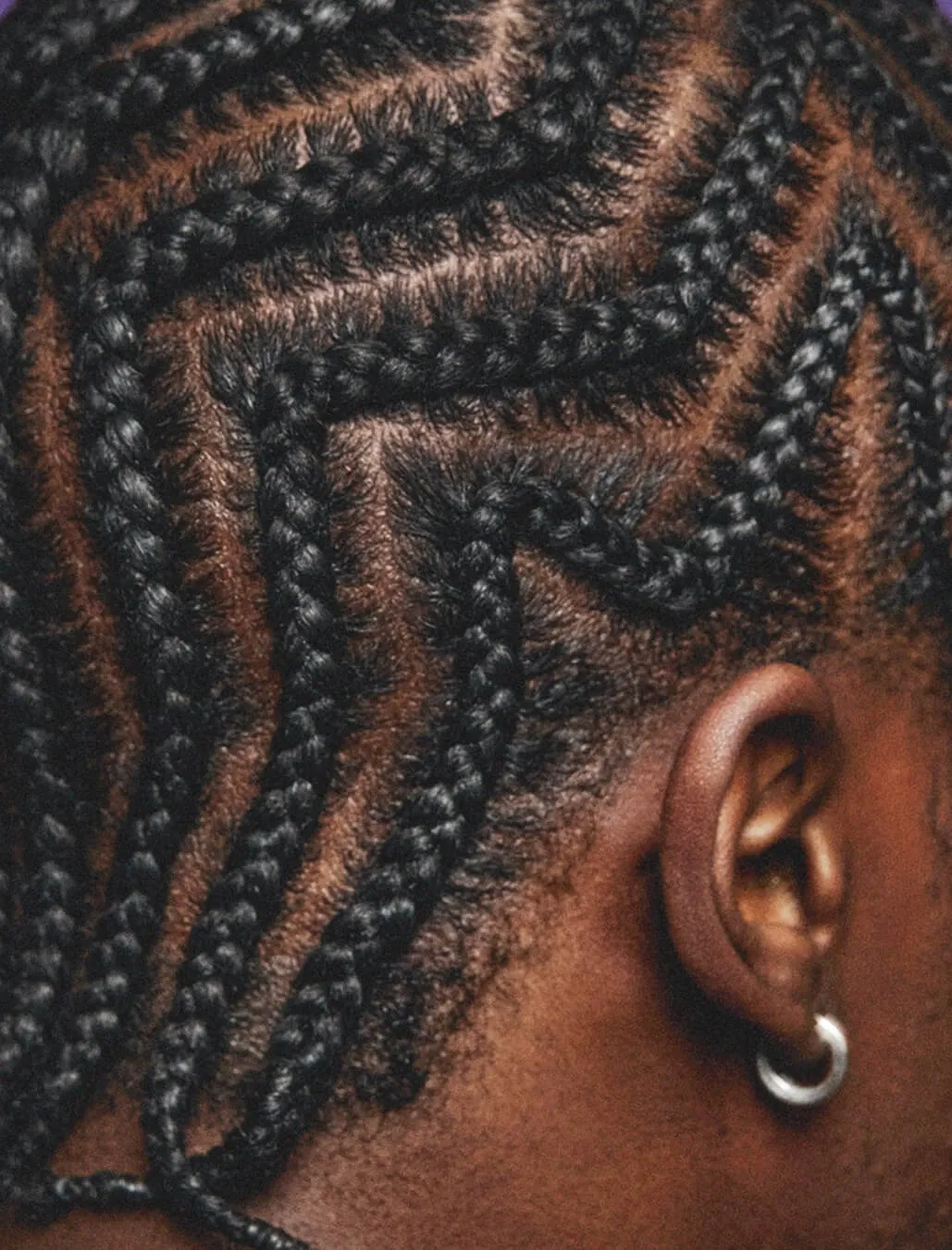 Closeup of the back right side of someone’s head showcasing their braids and small silver hoop earring