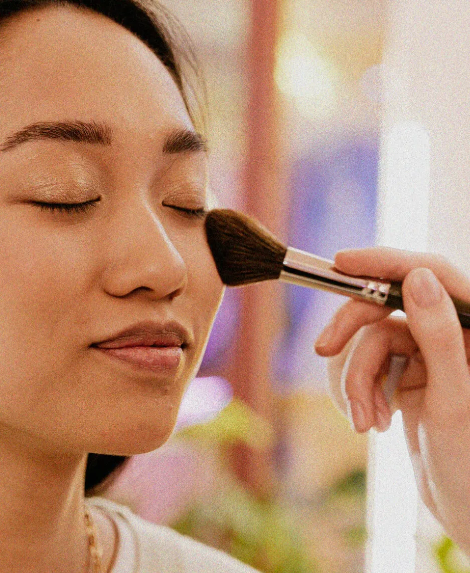 Woman getting makeup brushed onto her face
