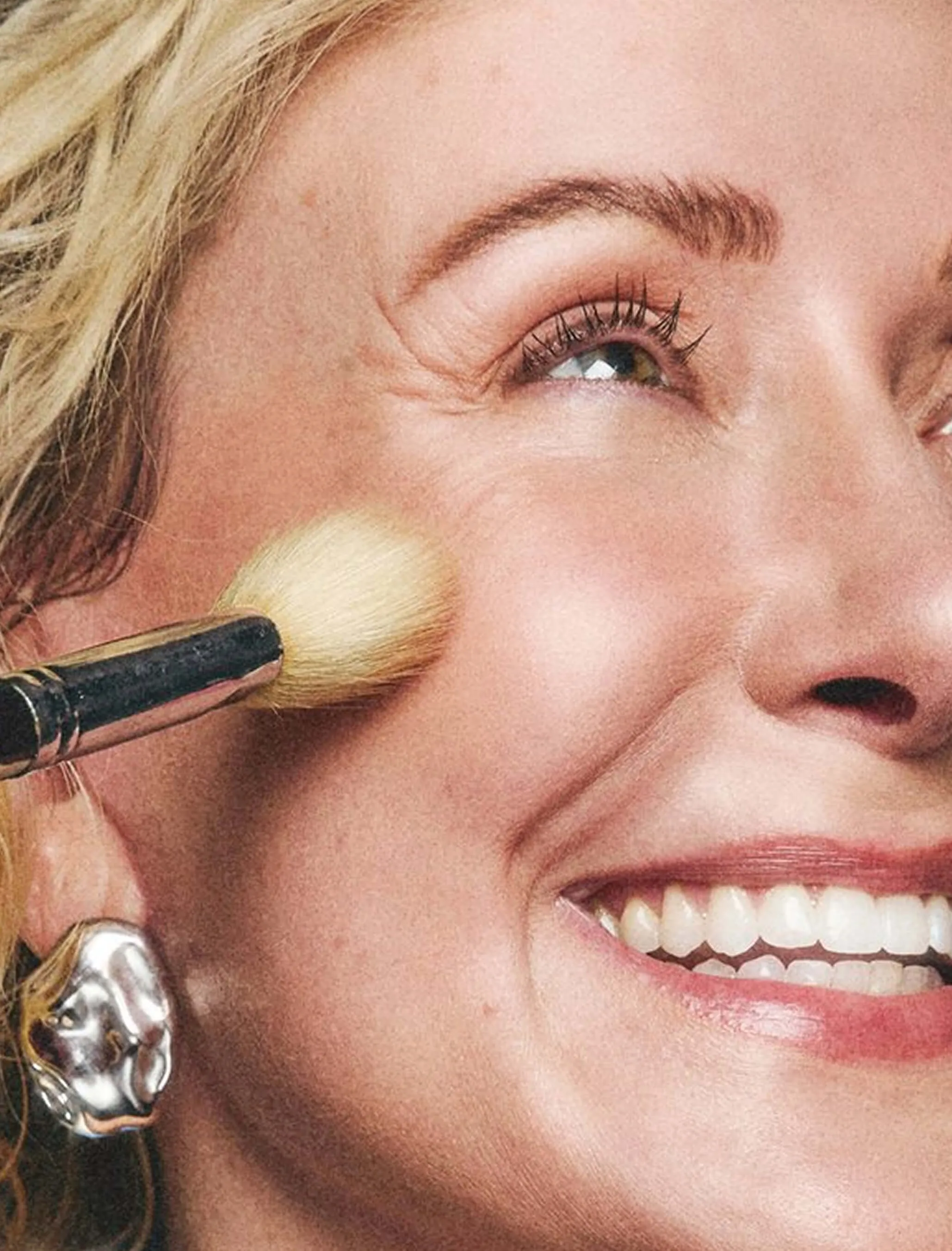 Closeup of woman getting makeup brushed along her cheek