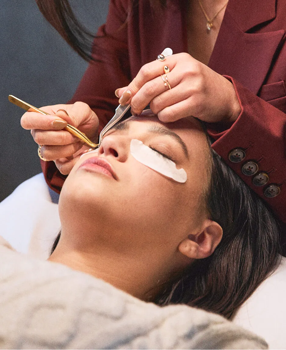 Closeup of lash artist applying lashes to her client