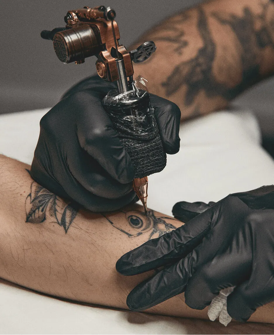 Closeup of a tattoo artist in black gloves drawing a tattoo on his client’s skin