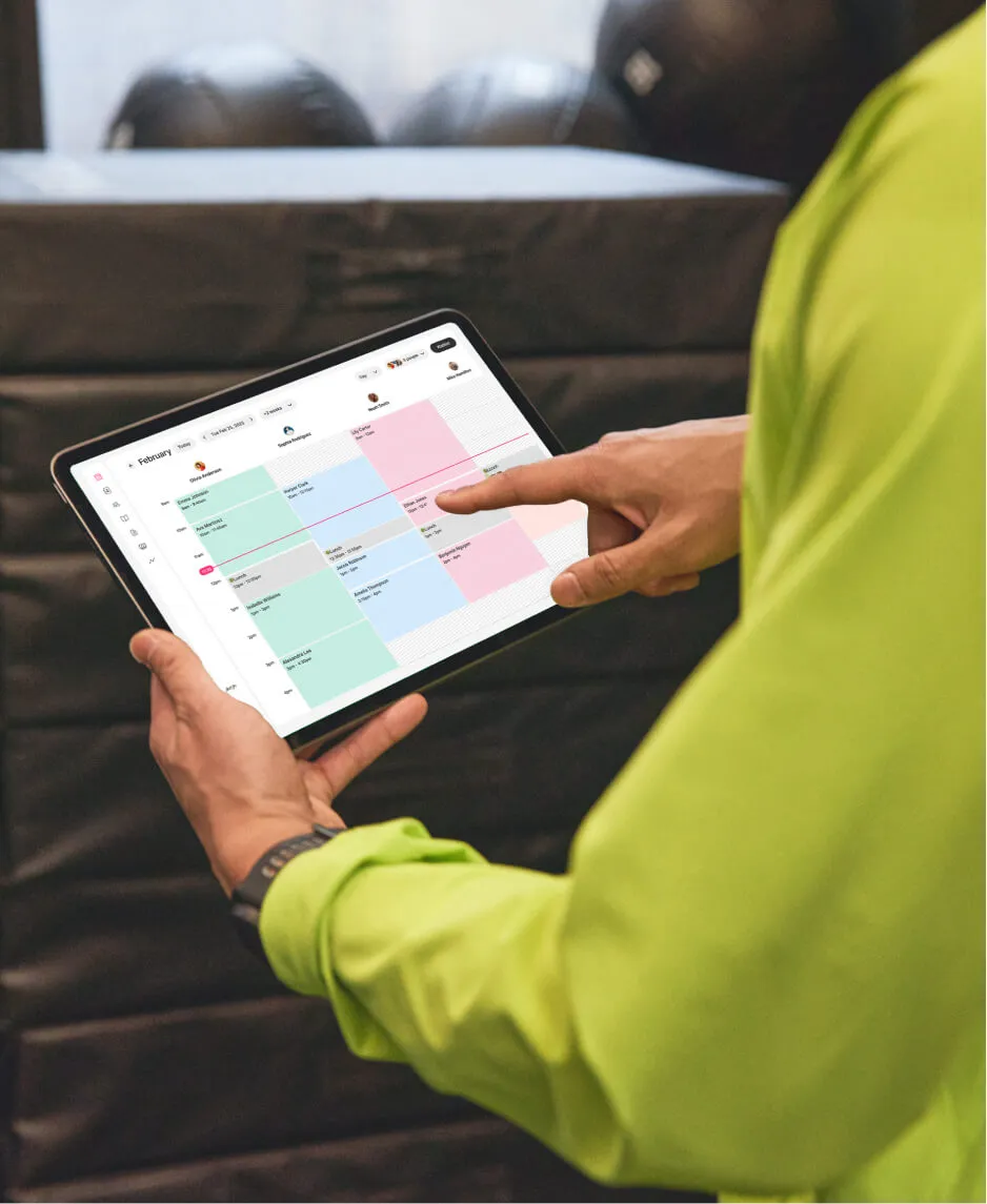 A fitness coach scrolling through their color-coded calendar in their personal trainer software
