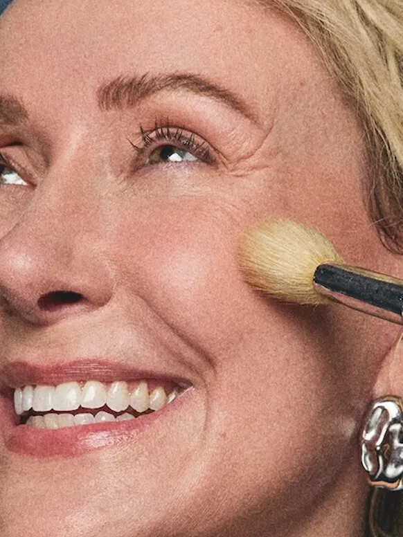 A woman having makeup applied to her cheek with a brush