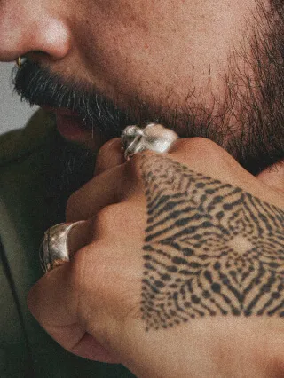 Closeup of a man’s tattooed hand and lower half of his face
