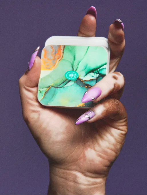 Closeup of a woman’s manicured hand holding a green marbled-pattern GlossGenius Tap & Go reader