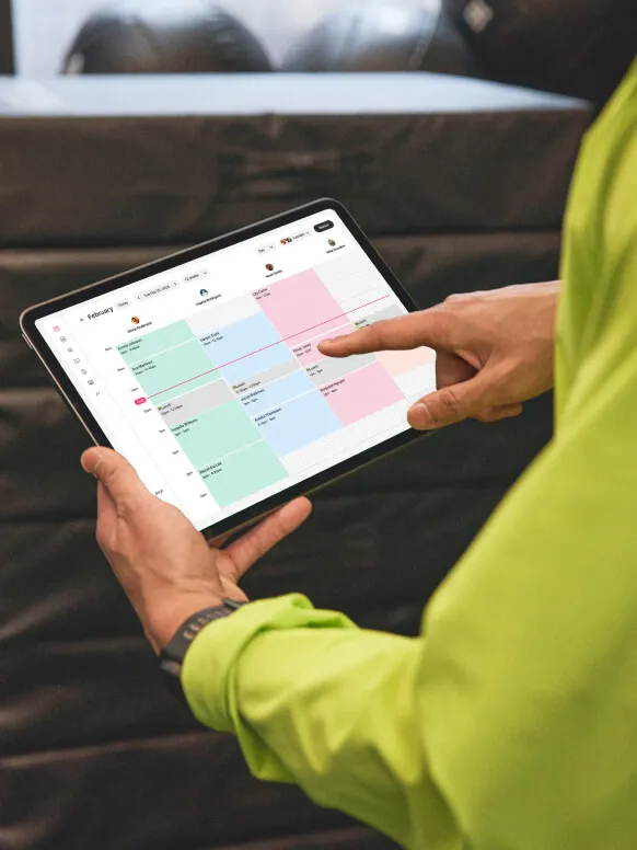 Hands holding a tablet displaying a color-coded calendar
