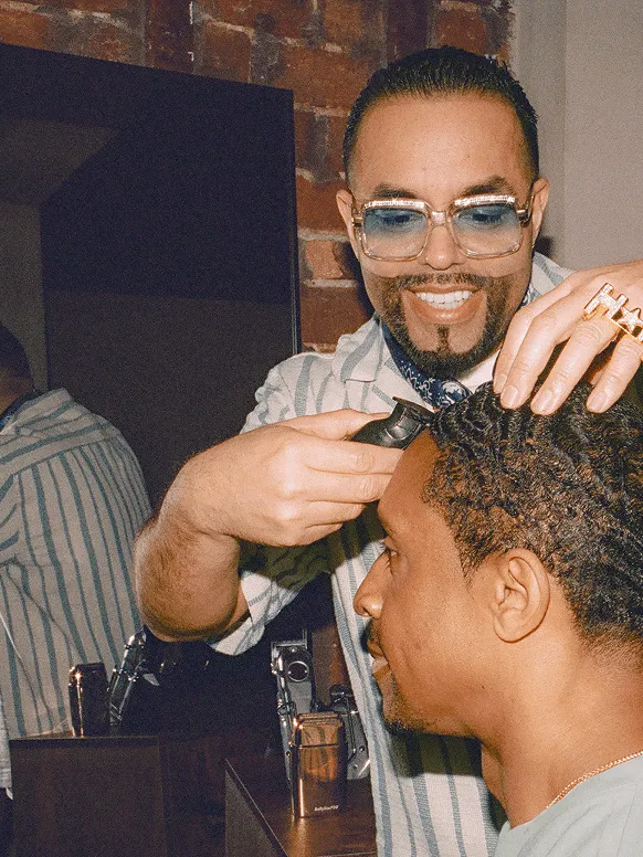 Image of a barber in blue-tinted glasses buzzing his client’s hair
