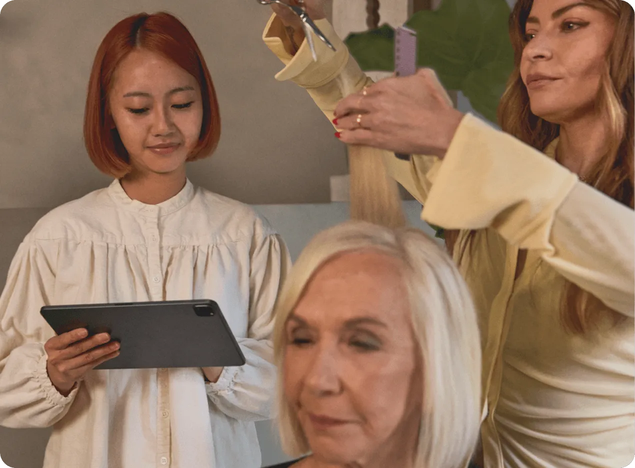 Image of hairstylist working on a client’s hair while another employee stands adjacent with a tablet