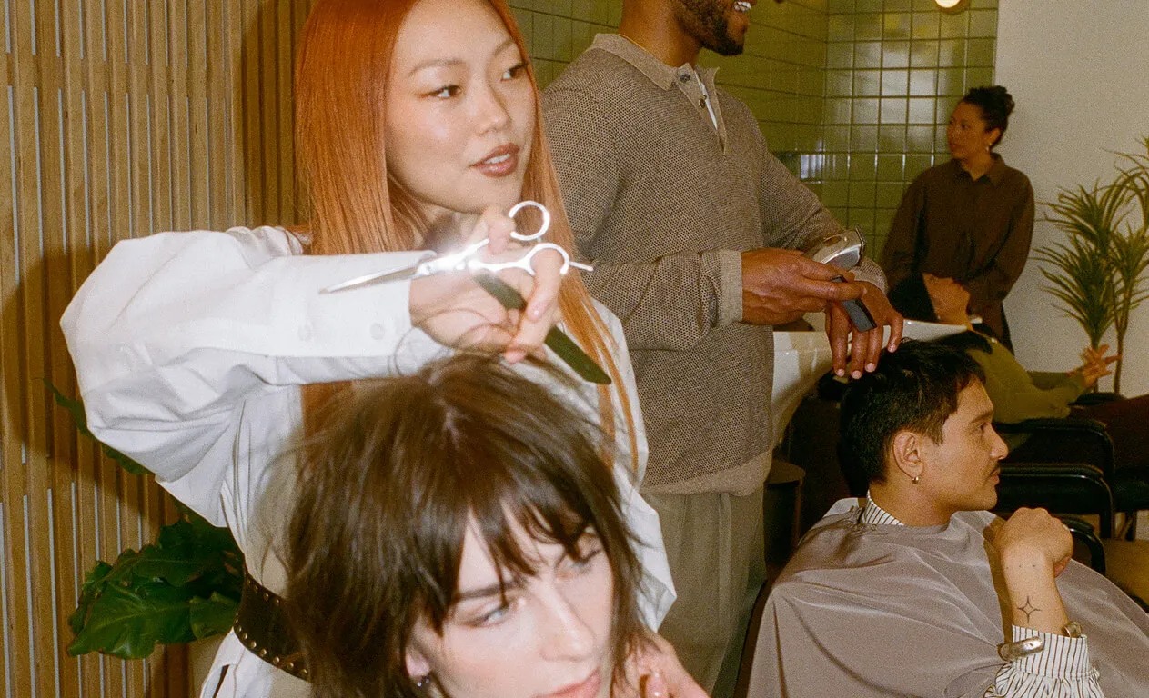 A hand holding a black credit card over a mobile phone held by two other hands