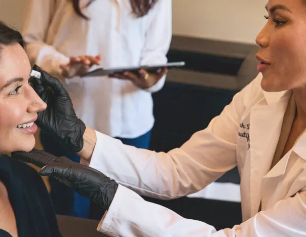 Image of an esthetician in a white coat providing treatment to a client