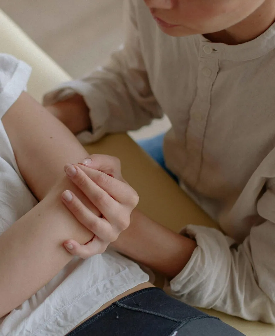 Closeup of a chiropractor's hands performing a spinal adjustment on a patient lying face-down on a treatment table.
