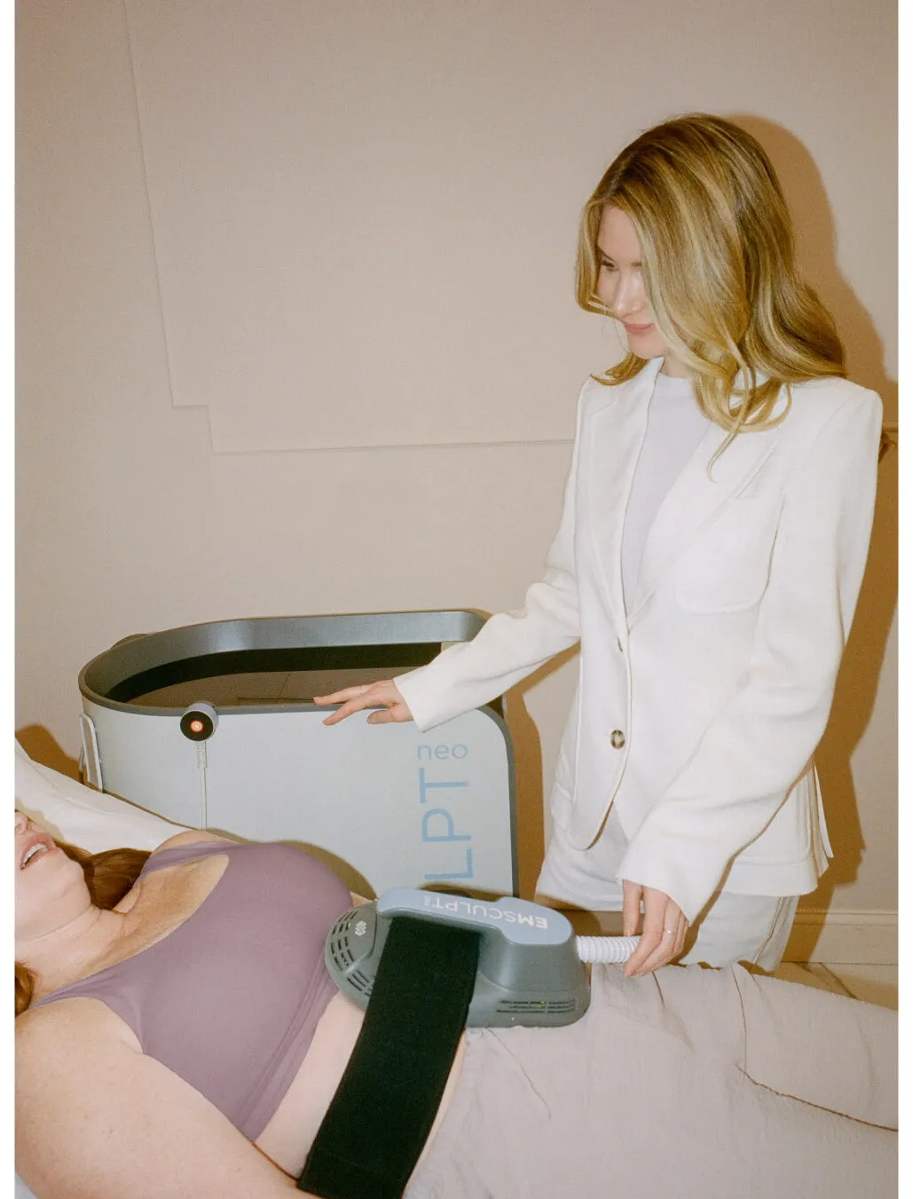 A clinician holding part of an EMSculpt machine over a client's stomach. 