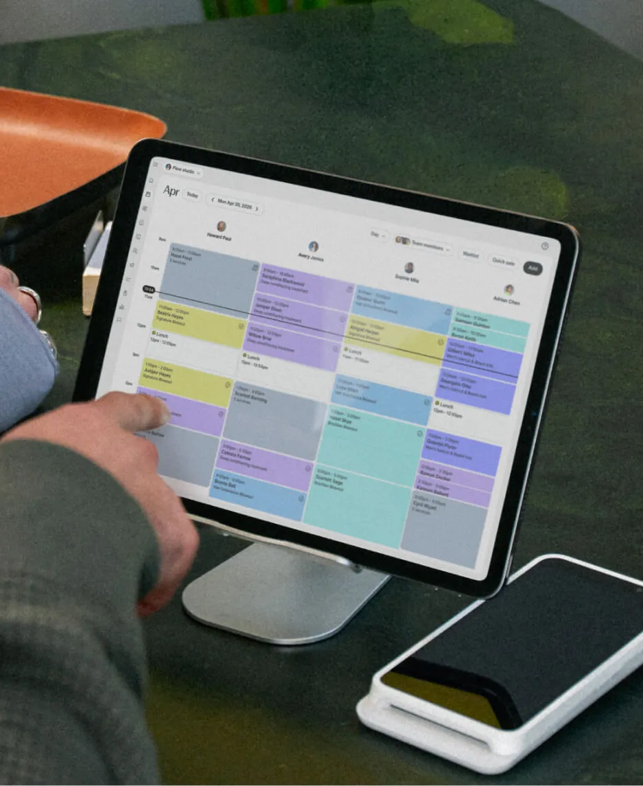 A tablet open to the GlossGenius behavioral health booking system calendar, with a therapist tapping an upcoming session.