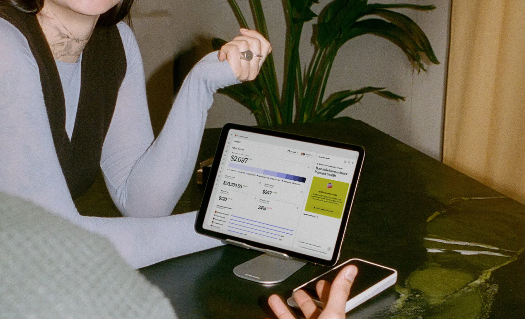 A hand holding a black credit card over a mobile phone held by two other hands