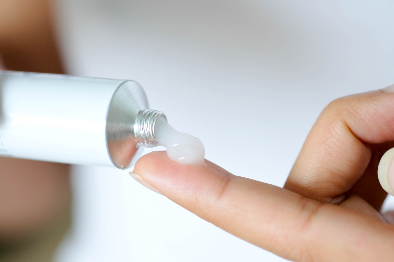 A white tube squirting ointment onto a fingertip after Blueberry Pediatrics medical consultation